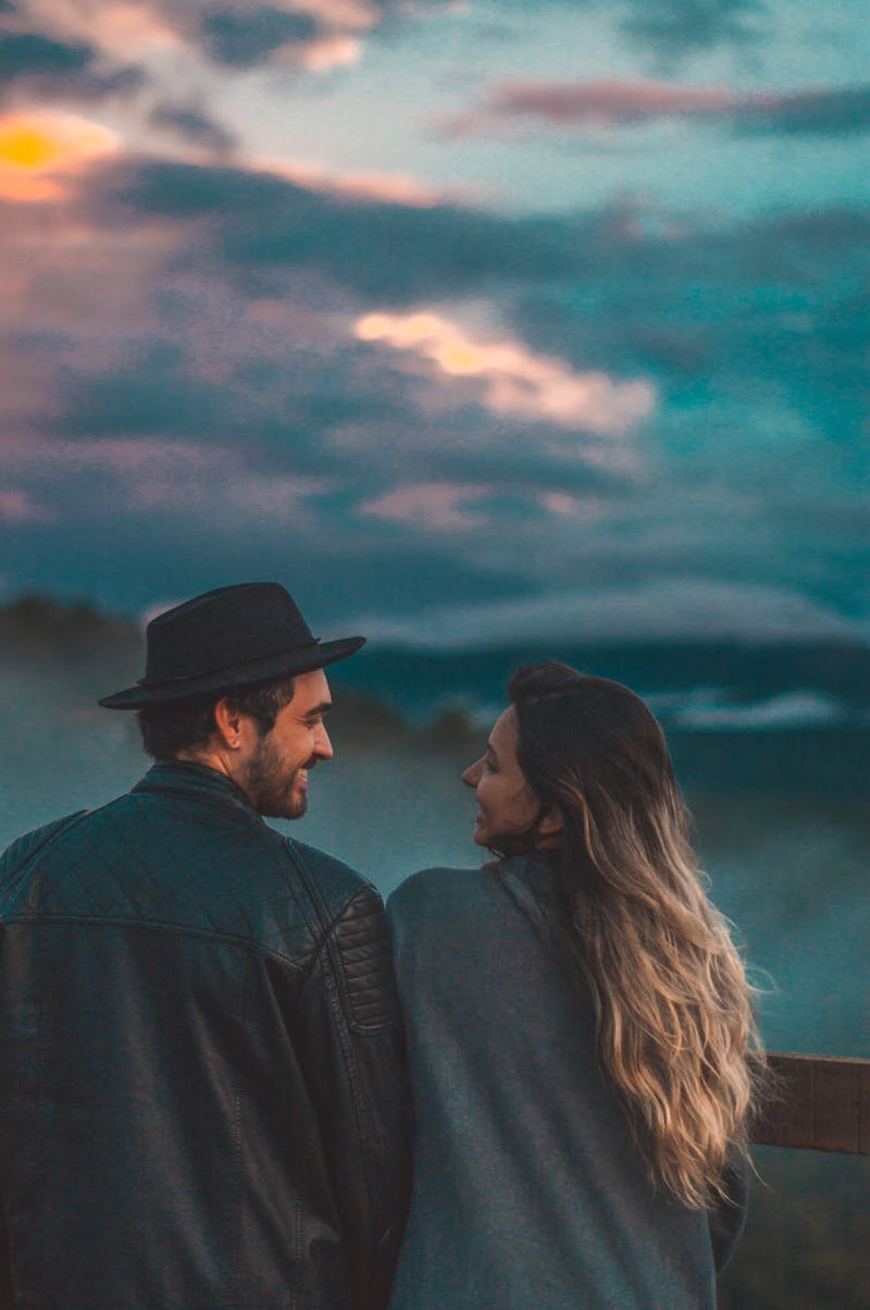 Couple de mariés enlacés sous la lumière dorée du coucher de soleil dans un champ